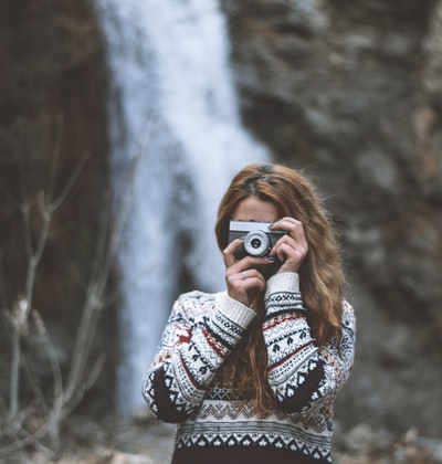 The woman dressed in black and white tribes sweater with black and white camera
